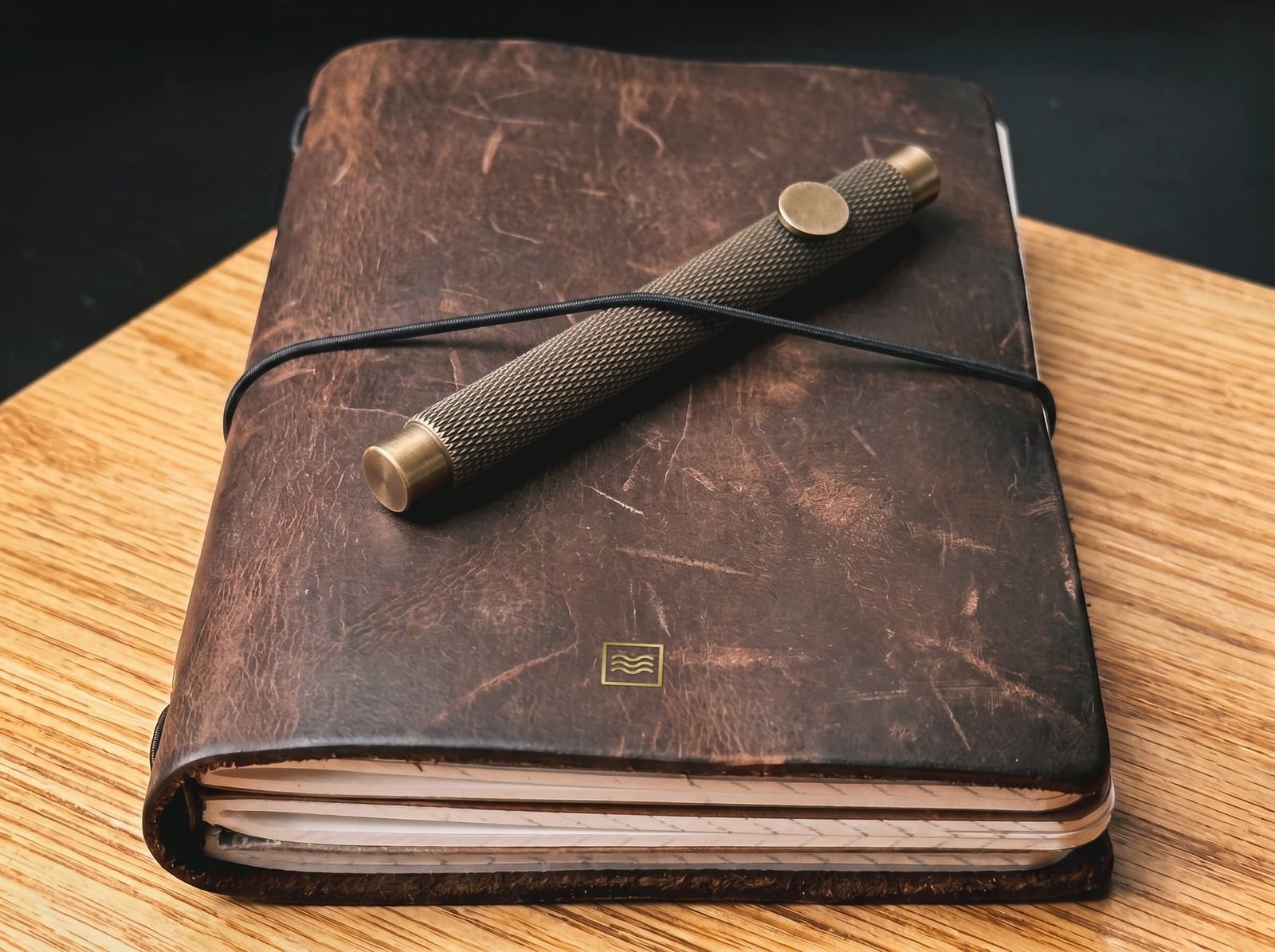 The brass pen with a knurled barrel, held by the elastic cord on a System cover in dark crazy horse leather.